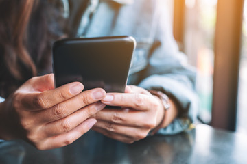 Closeup image of a woman holding , using and looking at mobile phone