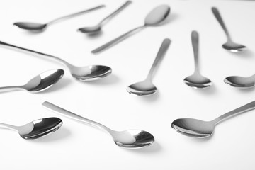 Set of new metal spoons on white background