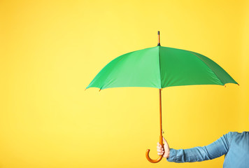 Woman holding modern colorful umbrella on yellow background, closeup. Space for text © New Africa