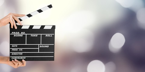 Hands holding clapper board on bokeh background