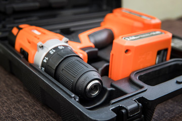 orange screwdriver or drill in a black container lies on the floor. Tool for tightening screws. Top...