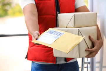Young courier holding parcels on doorstep, closeup. Delivery service - obrazy, fototapety, plakaty