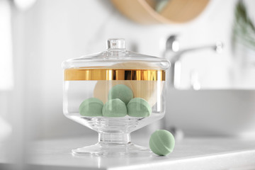 Jar with bath bombs and bath sponge on white countertop indoors