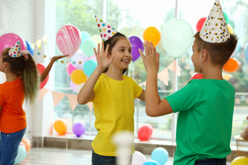 Happy children playing at birthday party in decorated room