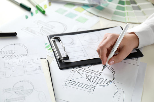 Female designer working at wooden table, closeup