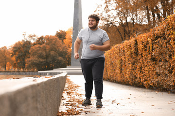 Young overweight man running in park. Fitness lifestyle - obrazy, fototapety, plakaty