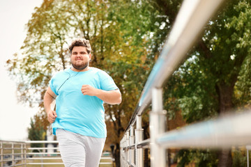 Young overweight man running outdoors. Fitness lifestyle