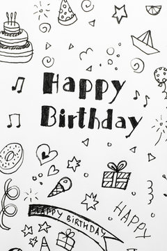 Words HAPPY BIRTHDAY and funny little pictures on white paper, top view