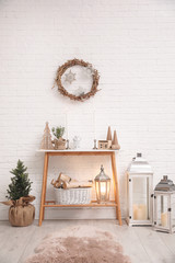 Fototapeta na wymiar Console table with Christmas decoration near brick wall. Idea for festive interior