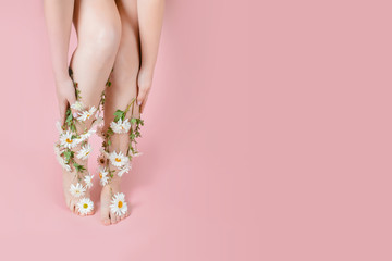 Legs in flowers camomiles on a pastel background. The concept of pain, swelling of the legs, varicose veins of pregnant women, laser hair removal	