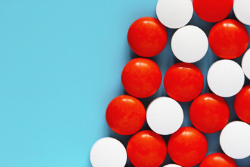 White and red medicine pills on blue background. Top view, copy space