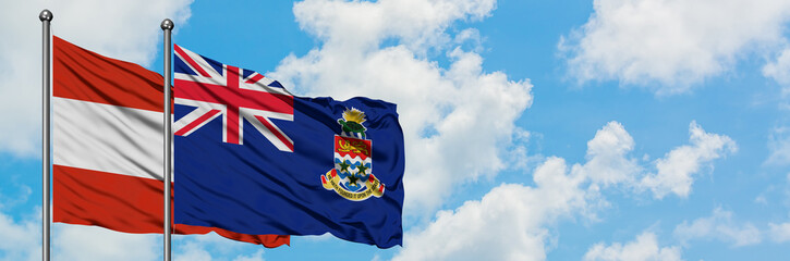 Austria and Cayman Islands flag waving in the wind against white cloudy blue sky together. Diplomacy concept, international relations.