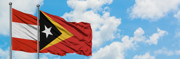 Austria and East Timor flag waving in the wind against white cloudy blue sky together. Diplomacy concept, international relations.