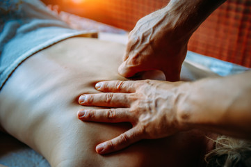 Acupressure massage in spa centre. Woman at acupressure back massage, masseur's hands close up....
