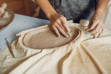 Woman in a pottery. Master make a dishes. Artist works with a clay
