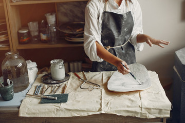 Woman in a pottery. Master make a dishes. Artist works with a clay