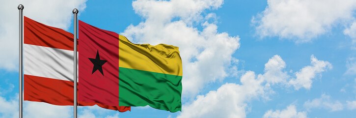 Fototapeta na wymiar Austria and Guinea Bissau flag waving in the wind against white cloudy blue sky together. Diplomacy concept, international relations.