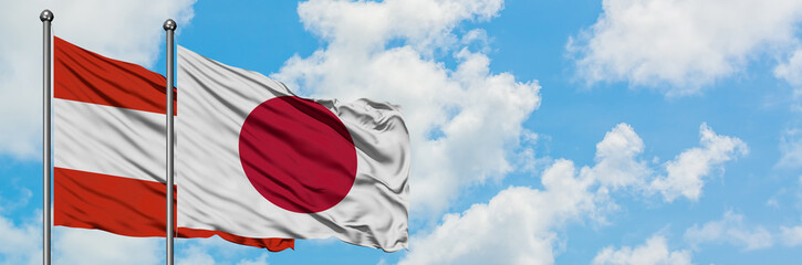 Austria and Japan flag waving in the wind against white cloudy blue sky together. Diplomacy concept, international relations.