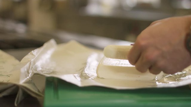 4K Slow motion close up of a a fresh cheese being sliced with a knife.  And filmed with a wide aperture