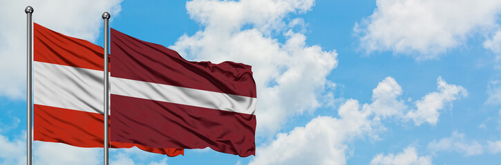 Fototapeta na wymiar Austria and Latvia flag waving in the wind against white cloudy blue sky together. Diplomacy concept, international relations.