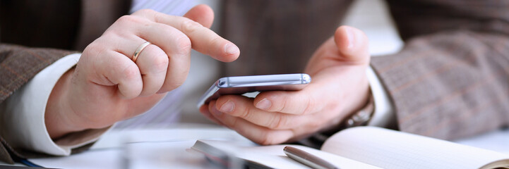 Male arm in suit hold phone and silver pen