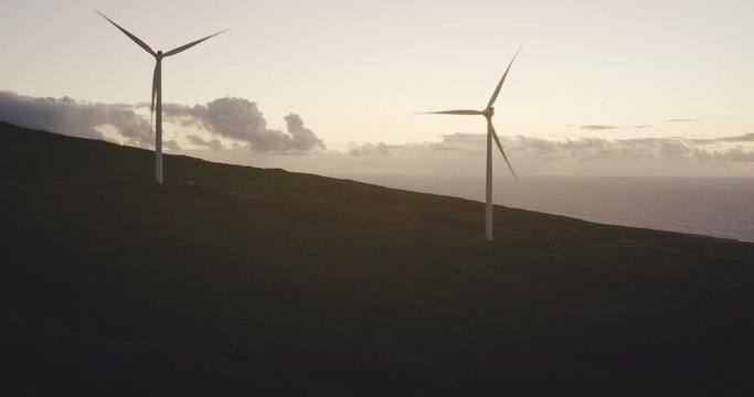 Aerial view of windmills spinning at sunrise, windmill farm creating electricity, green clean energy concept