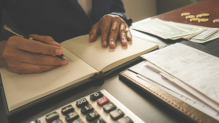 Woman with bills and calculator. Woman using calculator to calculate bills at the table in office....