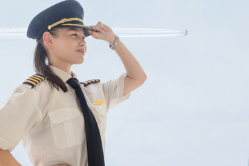 A female captain pilot standing next to an airplane at the airport. © globalmoments