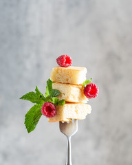 Stylish packed fluffy pancakes on fork decorated with three raspberries and  green mint leaves