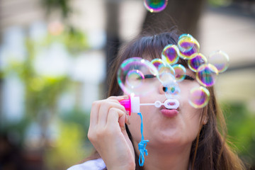 Young woman blowing soap bubbles in park outdoor.