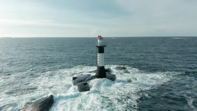 Aerial footage of lighthouse located in the middle of the sea, backward movement view