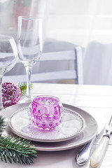 Place table setting for Christmas white table with purple decor elements with green branches Christmas tree