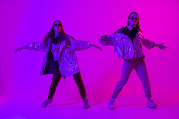 Young stylish girls dancing in the Studio on a colored neon background. Music dj poster design.