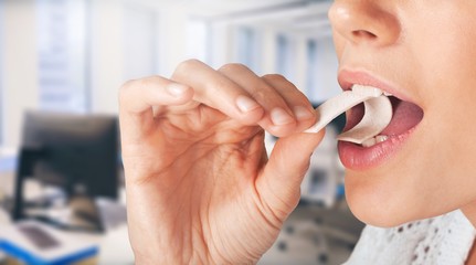 Close-up view of young woman putting chewing gum in her mouth