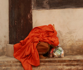 Buddhist monks belongings on a shelf at an ancient temple in Northern Thailand, showing his traditional alms container, some offerings and his saffron robe, Thailand, Southeast Asia