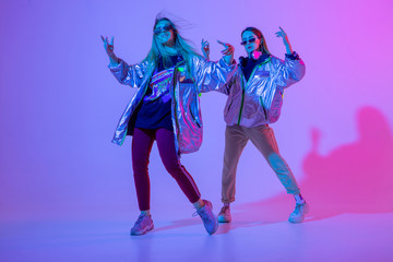 Fototapeta premium Młode stylowe dziewczyny tańczą w Studio na kolorowym tle neon. Projekt plakatu dj muzyki.