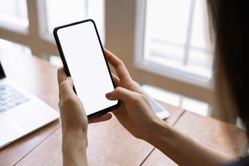 Cropped shot view of female hands holding smart phone with blank screen for your text message or information content.