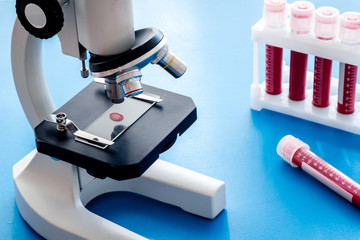 Blood testing. Samples viewing undermicroscope on blue background top view