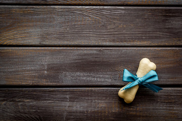 Small present for dogs. Chewing bones with bow on dark wooden background top view copy space