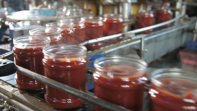 Fuming tomato paste banks moving on a metallic line without lids in tomato plant