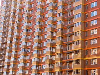 A huge residential high-rise brick building. Wall of small identical balconies. The theme of an...