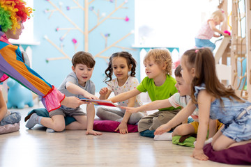 Clown amusing kids. Children are pulled to book