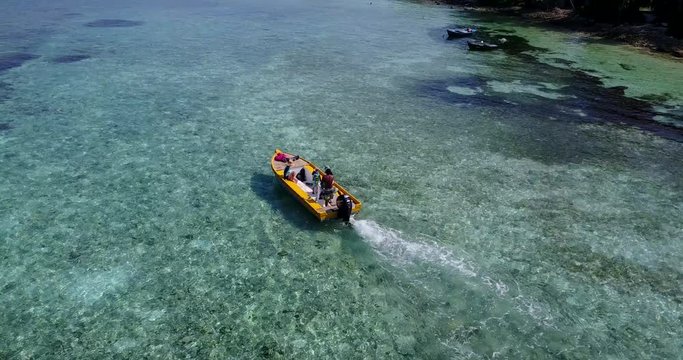Adventurer on a small yellow boat in open waters in Hawaii, with shallow reef in aquamarine transparent water