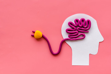 Brain charging and mental rest. Plug and cable leads to plastiline meanders on pink background top...