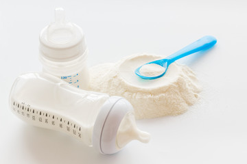 Baby food. Powder in spoon near baby bottle on white background