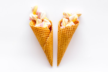 Sweet desserts. Marshmallows in ice cream waffle cone on white background top view