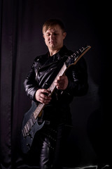 Fototapeta na wymiar Handsome guitarist playing his electric guitar on black background
