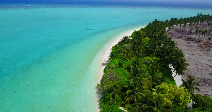 Panning from a deforested section of tropical island to reveal clear blue water in the Caribbean