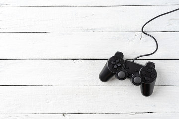 Overhead shot of video game controller on white wooden background with copyspace