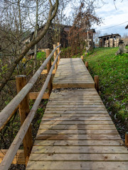 photo with pedestrian wooden stairs, tree leaves on footbridge, autumn day